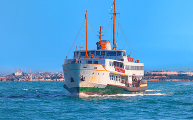 Wall Mural - Water trail foaming behind a passenger ferry boat in Bosphorus on the background famous historical Topkapi Palace - Istanbul, Turkey