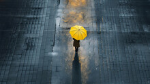 Solitary figure of a lonely woman with a yellow umbrella walking on a empty street. Urban atmosphere scene.