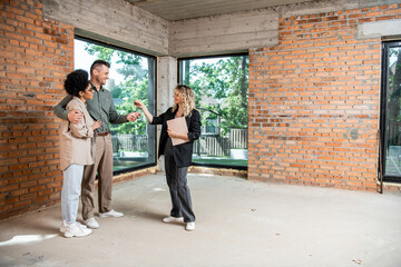 Wall Mural - real estate agent giving keys to interracial couple in new cottage with unfinished interior