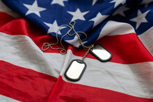 Dog Tags And The Flag Of America. Focused On The Dog Tags.