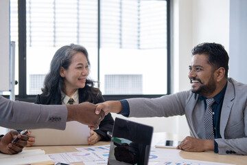 Wall Mural - Smiling diverse businesspeople shake hands get acquainted greeting at team meeting in office. Happy multiracial male colleagues employees handshake at briefing with coworkers. Acquaintance concept.