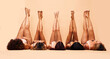 © Anela/peopleimages.com - Skincare, diversity and legs of women in studio for care, comparison and wellness on wall background. Difference, beauty and female friends relax in a line with feet up for glowing skin or treatment