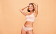 © Anela/peopleimages.com - Happy, lingerie and body of woman in studio isolated on a brown background mockup space. Smile, underwear and model in natural beauty, self love and confidence for positivity, health and wellness
