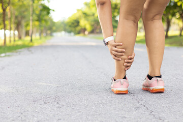 Injury from workout concept. Running sport injury leg pain. Runner woman massaging sore calf muscles during running training outdoor from pain. Female athlete with joint or muscle soreness.