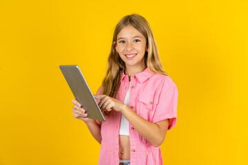 Photo of happy cheerful smart Beautiful caucasian kid girl wearing pink shirt hold tablet browsing internet