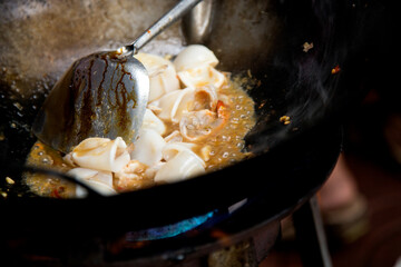 Wall Mural - Cooking squid with red curry at a street food stall in Bangkok, Thailand.