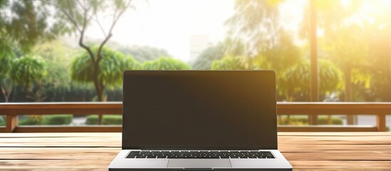 Poster - Blank screen laptop computer on wooden table with sunlight background