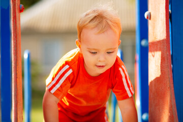 Wall Mural - little boy walking in park, child climbed onto the slide on playground to move down, leisure activity concept