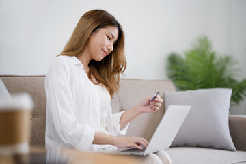 Wall Mural - Happy asian woman using laptop and credit card for online payment, E-commerce