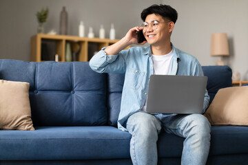 Poster - Asian guy in glasses with laptop communicating on phone indoor