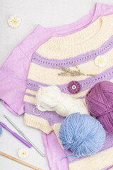 Wall Mural - Handmade crocheted baby t-shirt in lilac tones. Stuff contains thread, hooks, knitting needles