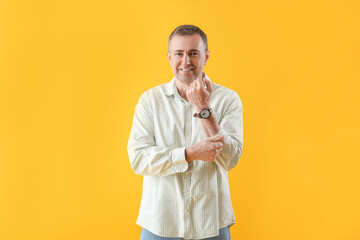Wall Mural - Mature man rolling up his sleeve on yellow background