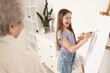 © Pixel-Shot - Little girl with her grandmother drawing at home