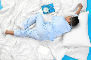 Wall Mural - Little African-American boy with soft blanket sleeping on blue background, top view