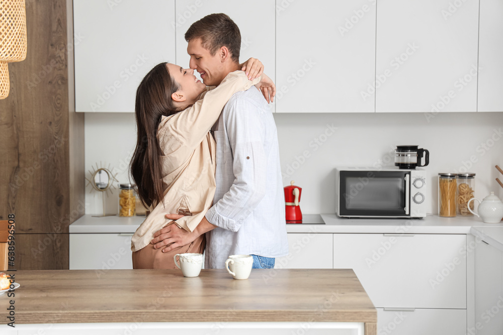 Happy young couple hugging in kitchen
