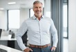© ibreakstock - Happy middle aged CEO standing confidently in office with hands in pockets