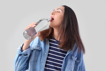 Sticker - Young woman with bottle of vodka on light background