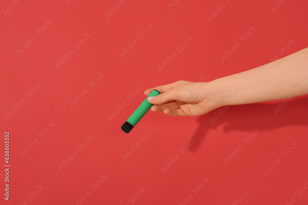 Woman holding electronic cigarette on red background