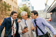 © Marko Geber - Diverse group of businessmen commuting to work and using a smart phone in the city