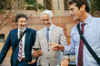 © Marko Geber - Diverse group of businessmen commuting to work and using a smart phone in the city