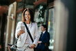 © Marko Geber - Mature caucasian businesswoman using a smart phone while commuting to work with a bicycle
