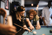 Young And Diverse Group Of Friends Playing Pool Together In A Bar