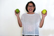 Asian woman standing with a big smile holding two freshly harvested mangoes