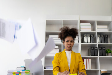 A stressful businesswoman throws papers at a business that doesn't go according to plan, too tired of her work.