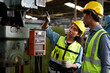 © offsuperphoto - worker or engineer training and teaching how to use machine control with coworker in factory