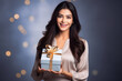© PRASANNAPIX - Indian woman holding gift box in hand on blur light background.