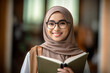 © AspctStyle - Portrait of attractive young muslim teacher wearing hijab smiling at camera. Young female wearing Hijab and holding a book