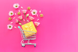 Fototapeta Mapy - Shopping cart with flowers and gift box over fuchsia background. Holidays shopping and sale concept