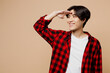 Young smiling happy fun man of Asian ethnicity he wear red shirt casual clothes hold hand at forehead look far away distance isolated on plain pastel light beige background studio. Lifestyle concept.