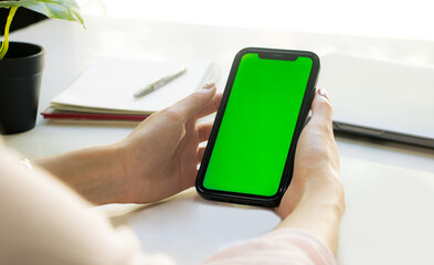 Poster - Close-up Woman sitting and holding blank screen mock up mobile phone on blur tabe background.