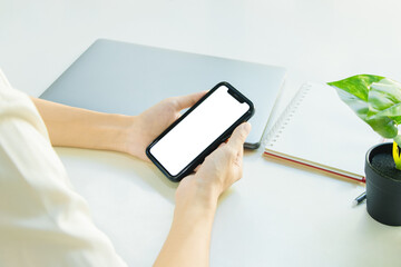 Poster - Businesswoman holding smartphone with blur table background. Blank white screen mobile phone for graphic display montage.
