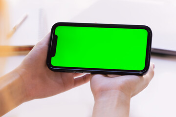 Poster - Close up view of a woman using blank green screen smartphone. Young adult using Internet, Play game, Watching online streaming with Mobile Phone Device.