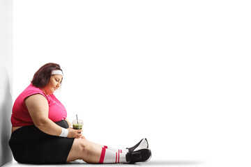 Poster - Sad overweight woman holding a healthy green and sitting on the ground