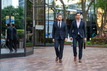 Wall Mural - Business men walking across the street on american city outdoor. Businessmen great partnership. Businessmen were constantly learning and growing.