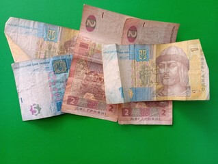 Ukrainian banknotes in denominations of five, two and one hryvnia on a green background
