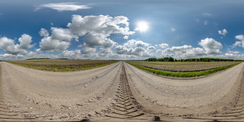Wall Mural - 360 hdri panorama on wet gravel road with marks from car or tractor tires with clouds on blue sky in
