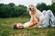 © standret - On the ground. Cute little girl is with golden retriever dog on the field