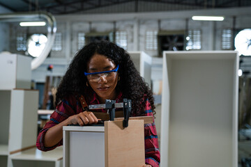 Wall Mural - Young woman working as carpenter in a small carpentry workshop, Small family business concept of young entrepreneurs