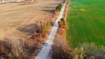 Drone view of highway road through America's farm fields. Aerial view of cars driving on asphalt road between golden trees in autumn and farm fields. Enjoy autumn nature and America's farm fields