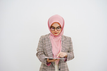 Wall Mural - Beautiful young muslim businesswoman pink hijab, company worker in glasses, smiling and holding digital tablet, standing over white background.