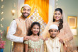 Happy smiling indian muslim parents with kids looking at camera during ramdan festival celebration - concept of traditional islamic ethnic wear, family bonding and religious culture
