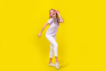 Sticker - Full size photo of good mood positive girl wear violet polo white trousers dancing in headphones isolated on yellow color background