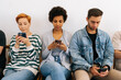 © dikushin - Cropped shot of bored multicultural and different ages people sitting in row using smartphones, waiting for job interview, human resources, employment or customers and electronic devices concept.