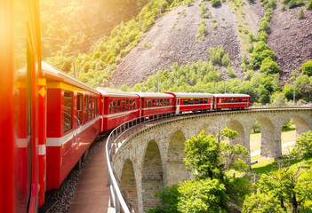 Wall Mural - Red train moving on vaiduct in summer in Switzerland