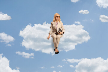 Poster - Woman holding books and sitting on a cloud up in the sky