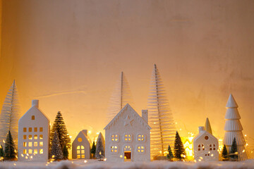 Wall Mural - Atmospheric miniature christmas village. Stylish little white houses and trees on snow blanket with glowing lights in evening. Christmas modern winter village, holiday banner. Happy Holidays!